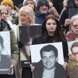 Personnes prenant part à une marche pour commémorer le 50e anniversaire du Bloody Sunday à Derry, portant des images des victimes.