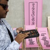 Ali a en main parcourt du bout de ses doigts la fiche du boîtier Virtuoz, un dispositif qui lui permet de se déplacer de façon autonome dans le bâtiment de la Comédie.