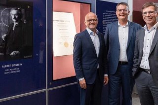 Le directeur exécutif de la Fondation Nobel, Vidar Helgesen, le recteur de l'Université de Zurich, Michael Schaepman, ainsi que le président de l'EPF Zurich, Joël Mesot, posent devant la vitrine exposant le certificat de doctorat d'Albert Einstein...