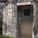 L'exposition "Aurélie Strumans. Sous la surface" commence devant le Musée d'art du Valais où une enseigne lumineuse, qui porte le mot "Operation Theater" ("salle d'opération" en anglais), surmonte une porte creusée dans la colline qui abritait aut...