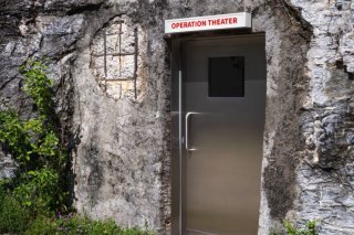 L'exposition "Aurélie Strumans. Sous la surface" commence devant le Musée d'art du Valais où une enseigne lumineuse, qui porte le mot "Operation Theater" ("salle d'opération" en anglais), surmonte une porte creusée dans la colline qui abritait aut...